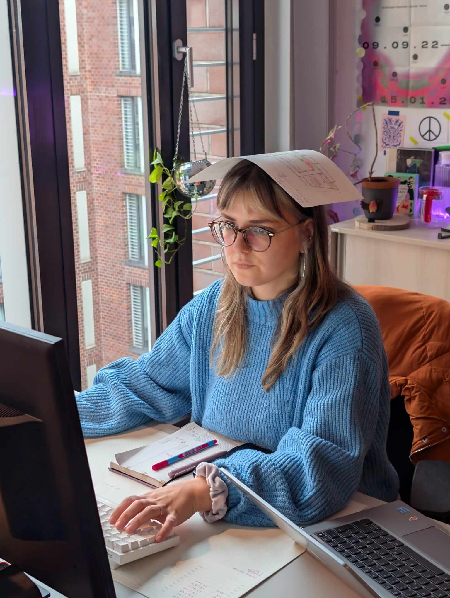 Das Foto zeigt Lio am Schreibtisch sitzend mit einem Blatt Papier auf dem Kopf.
