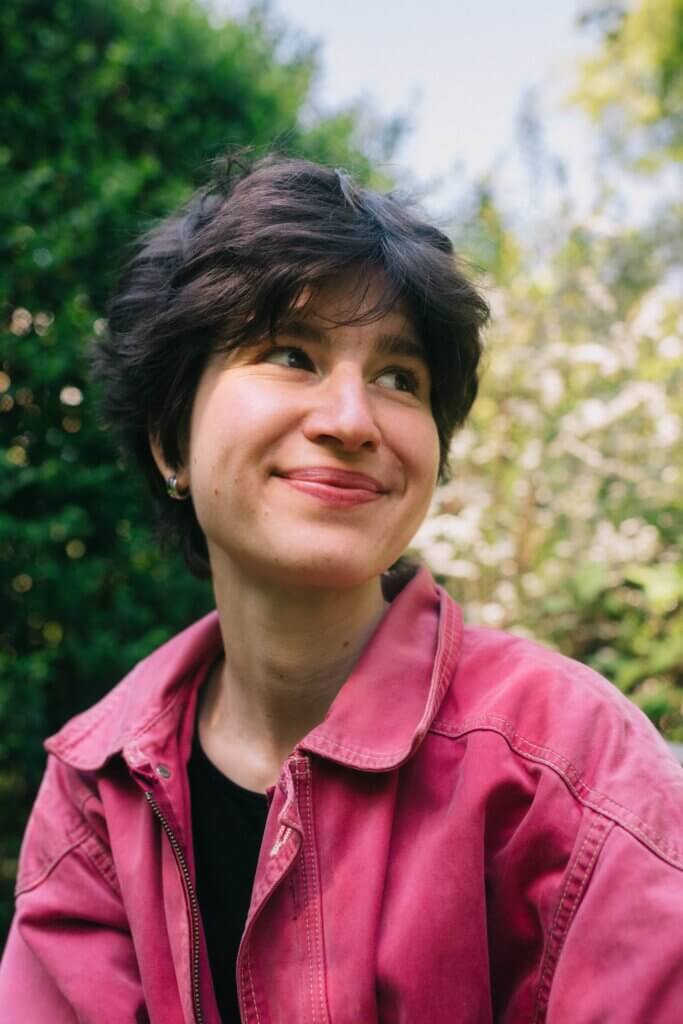 Das Foto zeigt Judith Kranz, Künstlerin bei Solarpunk, vor einem Hintergrund mit Bäumen.