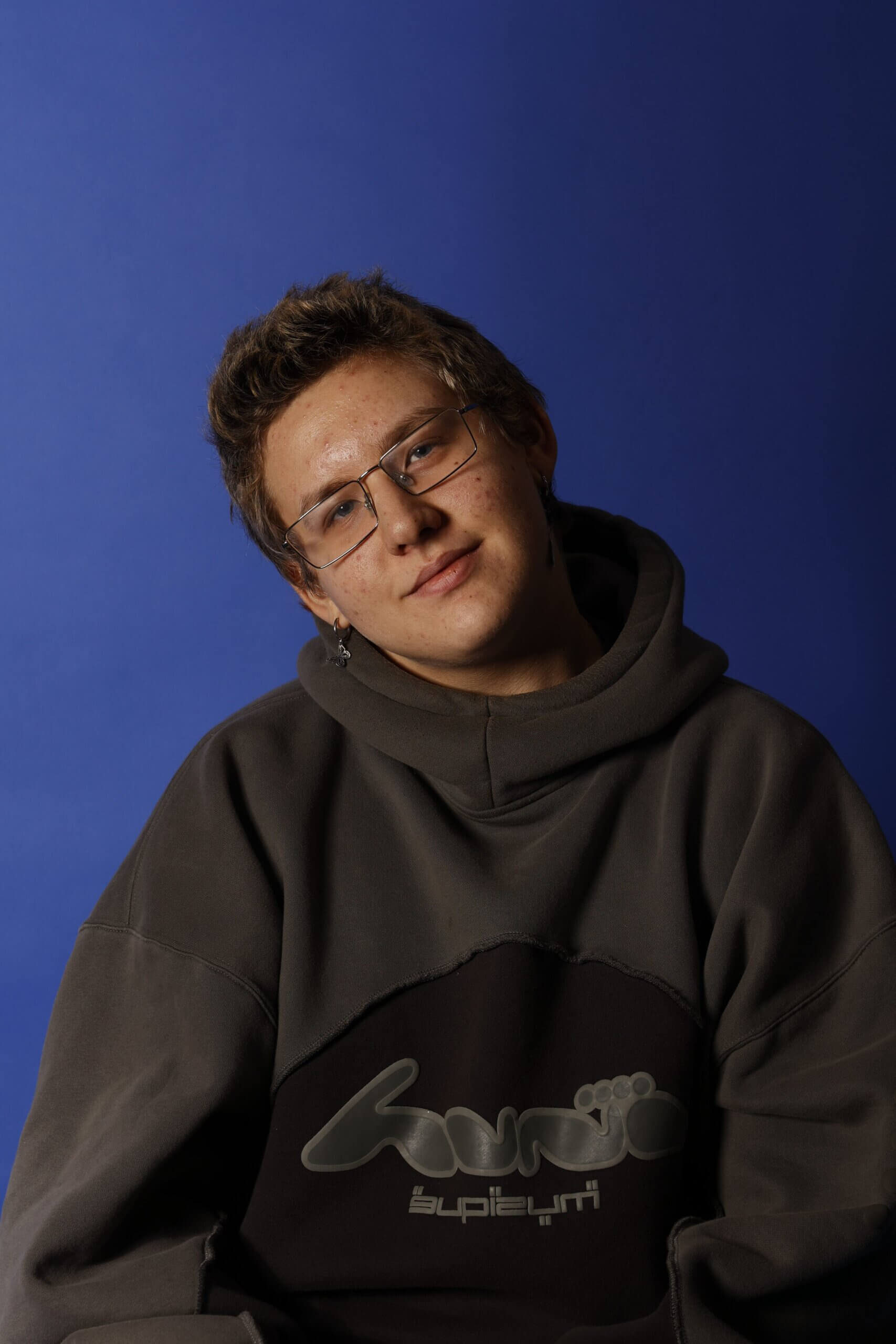 Das Bild zeigt Henri vor einem blauen Hintergrund wie er in die Kamera schaut.