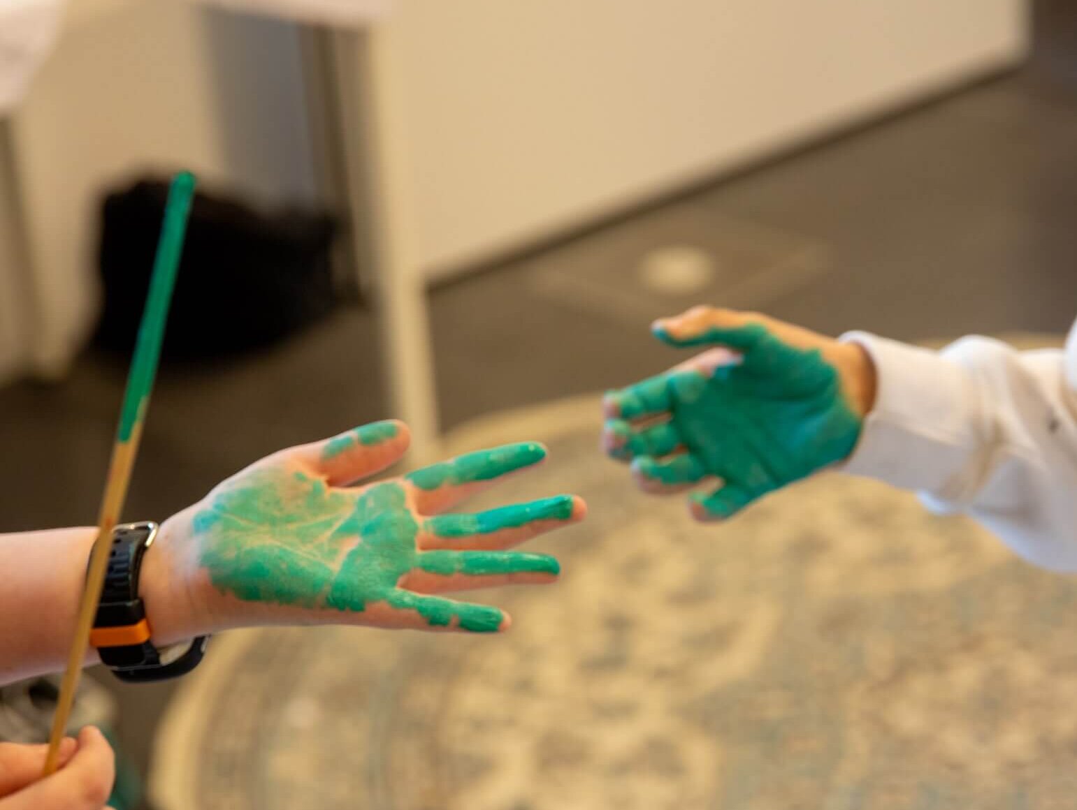 Das Bild zeigt zwei Kinderhände die mit grüner Farbe bemalt sind.